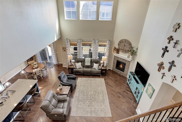 living area featuring a glass covered fireplace, a high ceiling, and wood finished floors