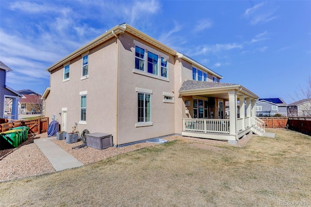 back of house featuring a porch, a yard, fence, and stucco siding