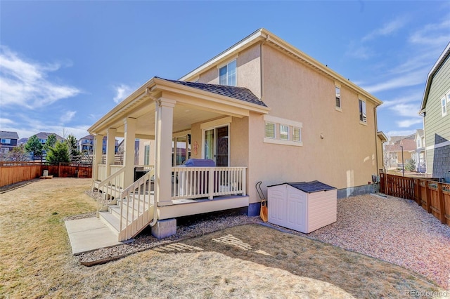 back of house featuring stucco siding, an outbuilding, a storage shed, and a fenced backyard