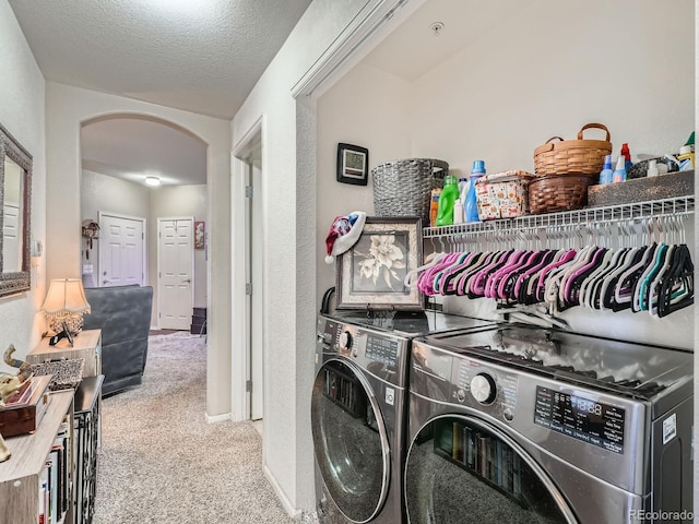 laundry area featuring washer and dryer, light colored carpet, and a textured ceiling