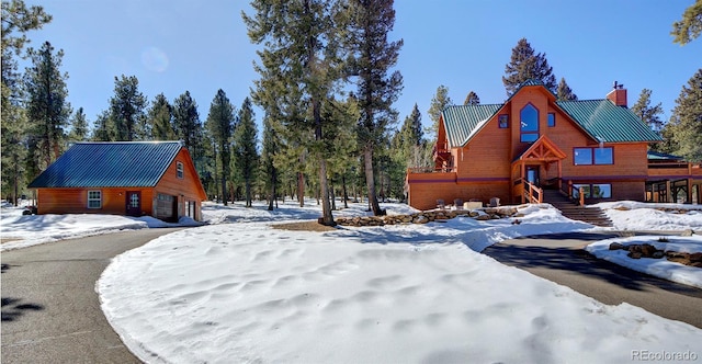 306 Spring Dr, Pine, CO 80470 - snow covered property with a chimney, metal roof, and a detached garage
