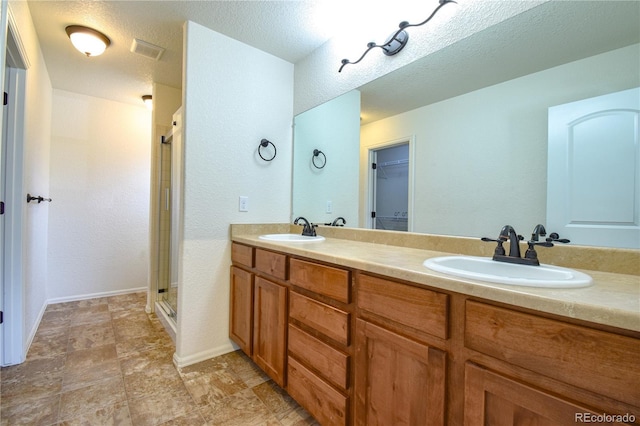 1057 Mt Oxford Ave, Severance, CO 80550 - bathroom featuring a stall shower, double vanity, a walk in closet, stone finish floors, and a textured wall