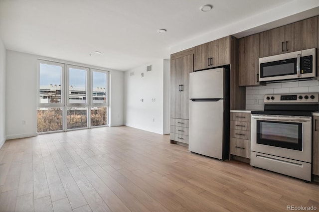 kitchen with light wood-type flooring, backsplash, and appliances with stainless steel finishes