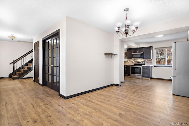 kitchen featuring stainless steel appliances, light countertops, light wood-type flooring, backsplash, and an inviting chandelier