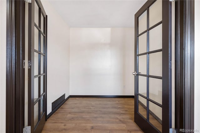 unfurnished room with french doors, visible vents, baseboards, and wood finished floors