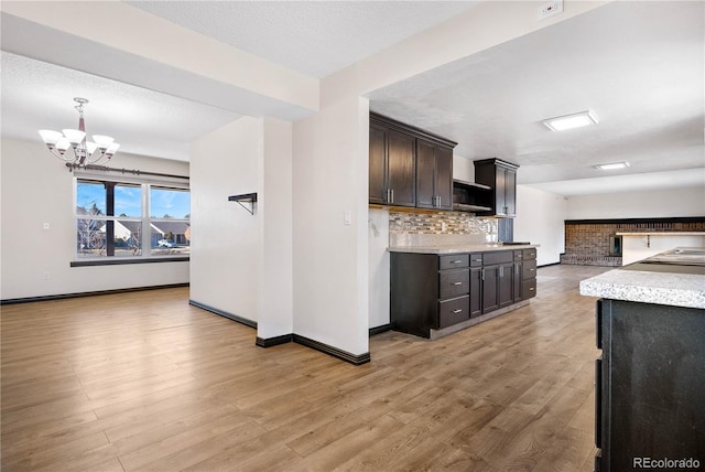 kitchen featuring open floor plan, stainless steel microwave, backsplash, and light wood finished floors