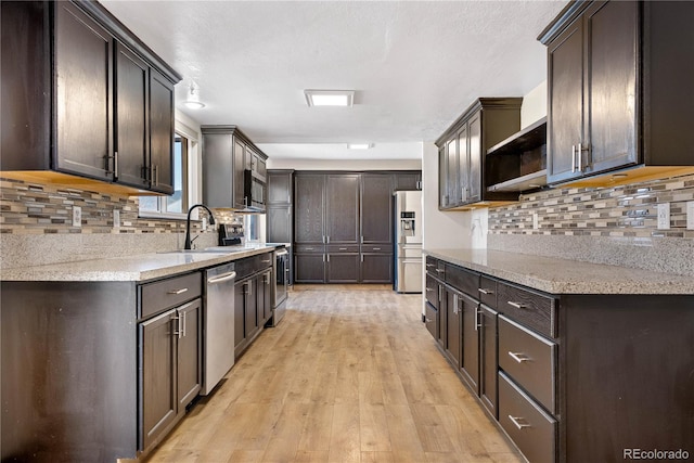 kitchen featuring light wood-style flooring, dark brown cabinetry, stainless steel appliances, a sink, and open shelves