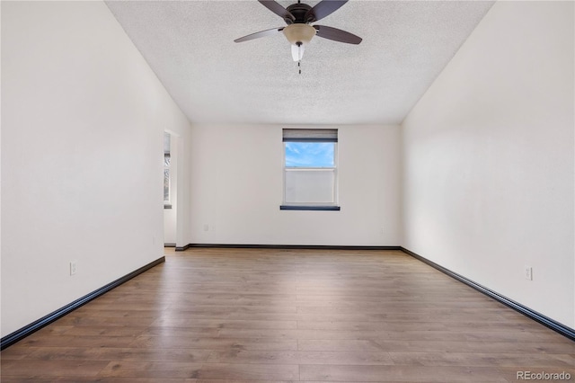 empty room featuring a textured ceiling, baseboards, and wood finished floors