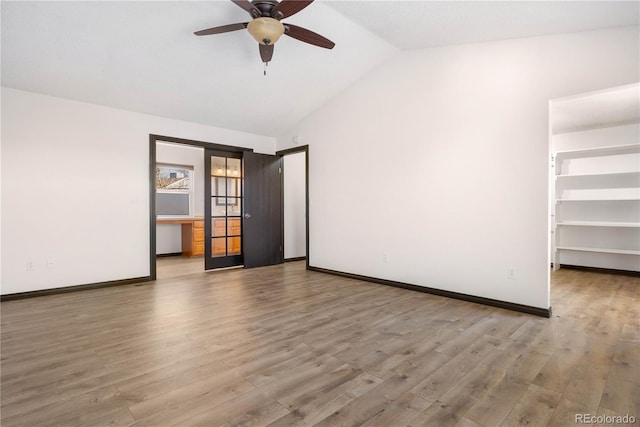 spare room featuring a ceiling fan, baseboards, vaulted ceiling, and wood finished floors