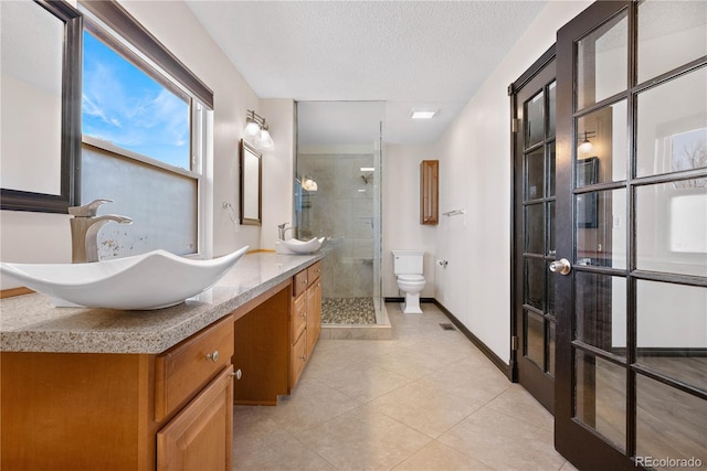 full bathroom with a textured ceiling, toilet, vanity, a shower stall, and tile patterned floors