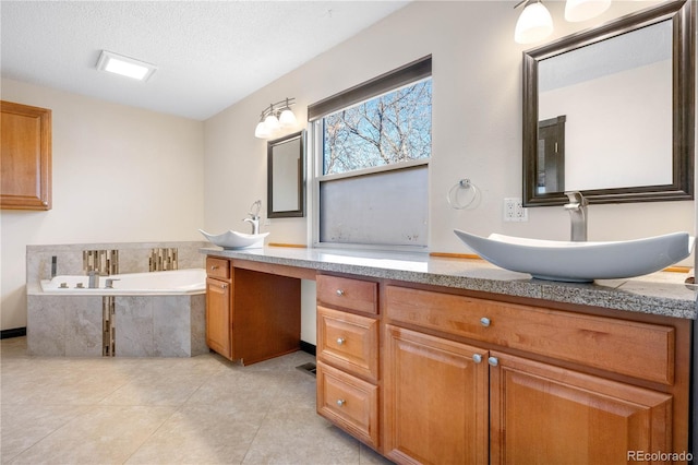 full bath featuring a textured ceiling, tile patterned flooring, a garden tub, and vanity