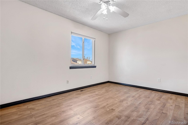 spare room featuring visible vents, baseboards, ceiling fan, a textured ceiling, and light wood-type flooring