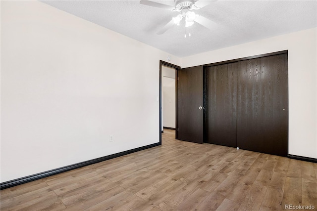 unfurnished bedroom featuring light wood finished floors, baseboards, a ceiling fan, a textured ceiling, and a closet