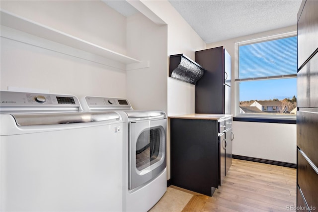 laundry room featuring a textured ceiling, laundry area, washer and clothes dryer, and light wood-style floors