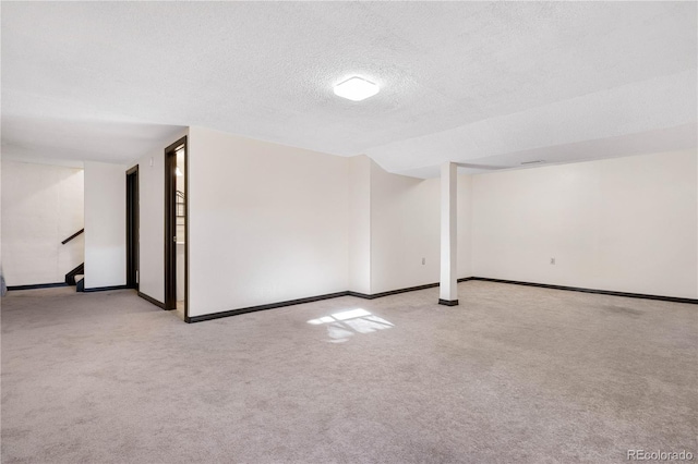 carpeted spare room featuring stairway, a textured ceiling, and baseboards