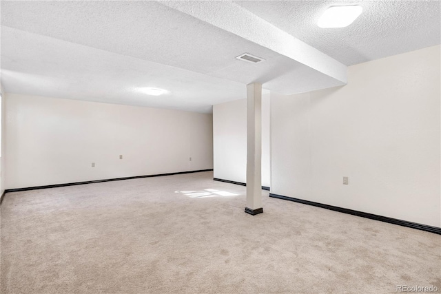 finished basement with carpet floors, baseboards, visible vents, and a textured ceiling