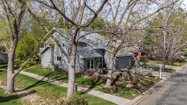 view of property hidden behind natural elements featuring an attached garage and a front yard