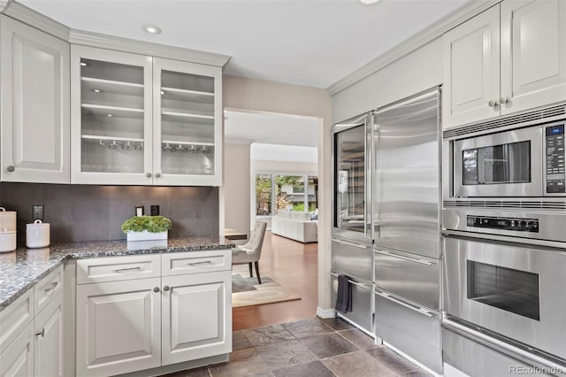 kitchen featuring glass insert cabinets, white cabinetry, built in appliances, backsplash, and a warming drawer