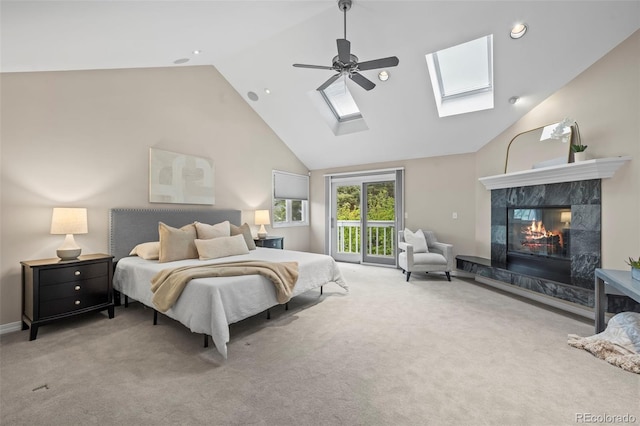 carpeted bedroom with a skylight, a high end fireplace, recessed lighting, ceiling fan, and access to outside