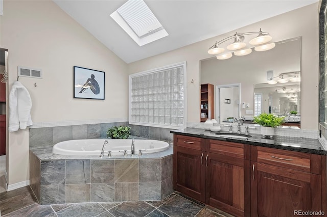 bathroom featuring vanity, lofted ceiling with skylight, a garden tub, and visible vents