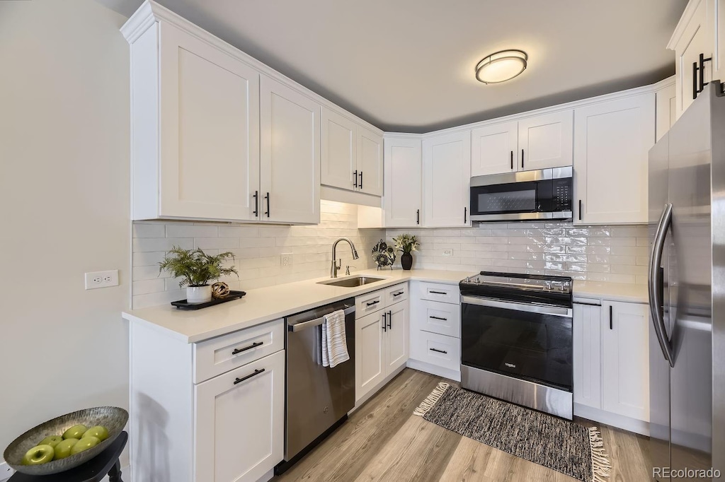 kitchen with tasteful backsplash, sink, white cabinets, and appliances with stainless steel finishes