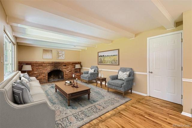 living room with beam ceiling, wood-type flooring, and a brick fireplace