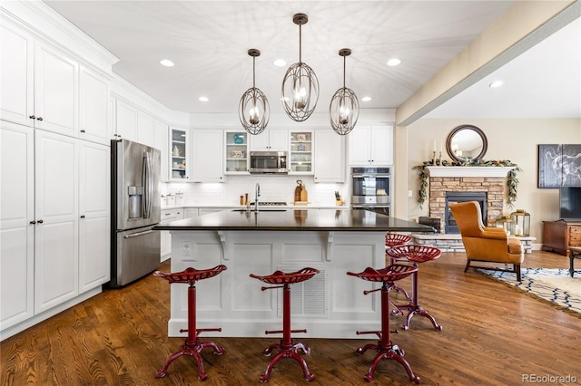 kitchen featuring backsplash, appliances with stainless steel finishes, a kitchen island with sink, and white cabinets