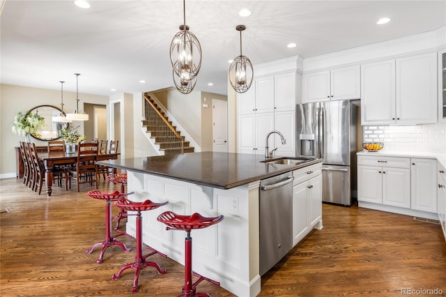 kitchen featuring stainless steel appliances, sink, a kitchen island with sink, and white cabinets