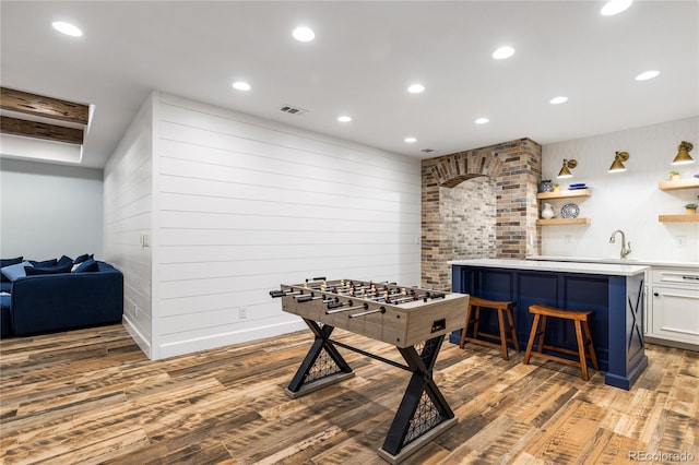 playroom featuring sink, light hardwood / wood-style flooring, and wood walls