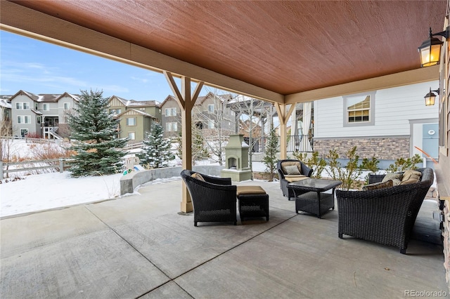 snow covered patio featuring an outdoor living space with a fireplace