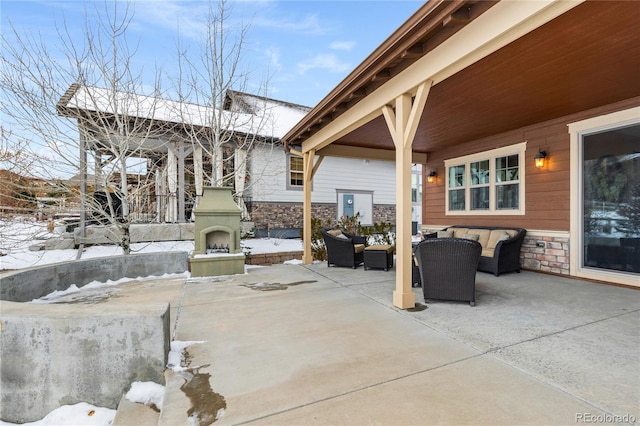 snow covered patio with an outdoor living space with a fireplace