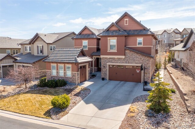 craftsman inspired home featuring a tile roof, stone siding, a residential view, concrete driveway, and a garage