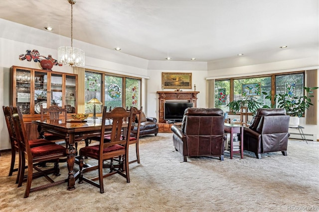 carpeted dining area featuring a chandelier, a baseboard heating unit, and a healthy amount of sunlight