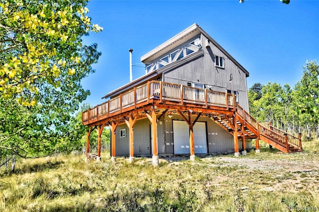 rear view of property featuring stairway, a wooden deck, and a garage