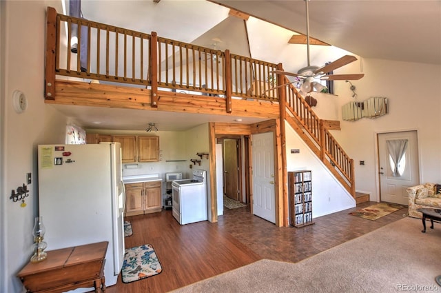 interior space featuring ceiling fan, dark carpet, washer / dryer, freestanding refrigerator, and high vaulted ceiling