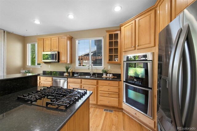 4821 Bluegate Dr, Highlands Ranch, CO 80130 - kitchen with stainless steel appliances, a sink, light wood-type flooring, recessed lighting, and glass insert cabinets