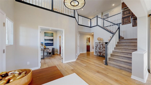 foyer with baseboards, a high ceiling, recessed lighting, stairs, and light wood-style floors