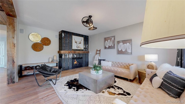 living room featuring wood finished floors, visible vents, and a tile fireplace