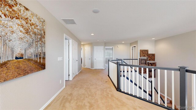 hallway with visible vents, baseboards, light colored carpet, an upstairs landing, and recessed lighting