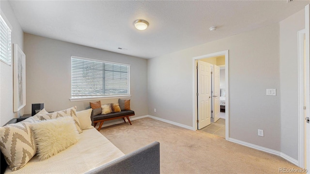 living area featuring light carpet and baseboards