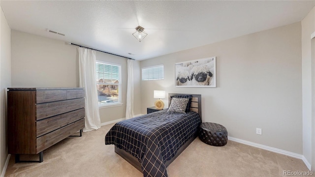 bedroom featuring visible vents, light colored carpet, and baseboards