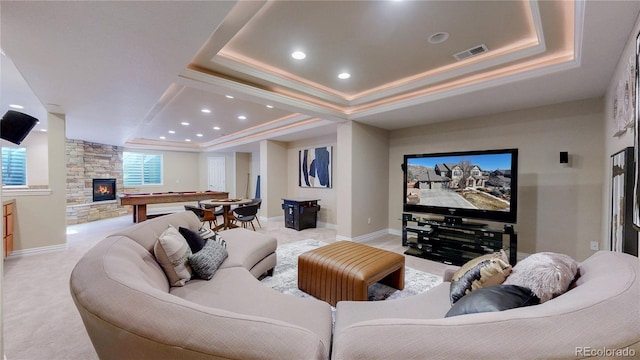 cinema with visible vents, ornamental molding, a fireplace, a raised ceiling, and light colored carpet