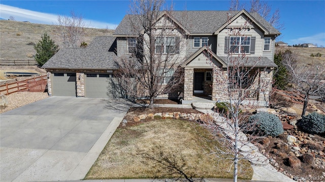 craftsman house with driveway, stone siding, fence, a shingled roof, and a garage