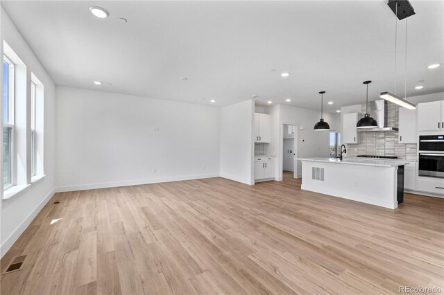 223 Washington St, Erie, CO 80516 - unfurnished living room with recessed lighting, light wood-style floors, a sink, and baseboards
