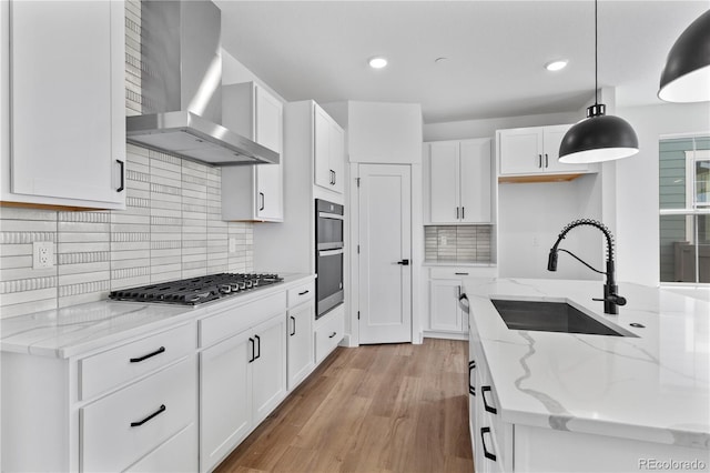 223 Washington St, Erie, CO 80516 - kitchen with wall chimney exhaust hood, appliances with stainless steel finishes, a sink, white cabinets, and hanging light fixtures