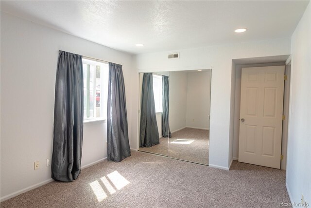 unfurnished bedroom featuring light carpet, a closet, and a textured ceiling