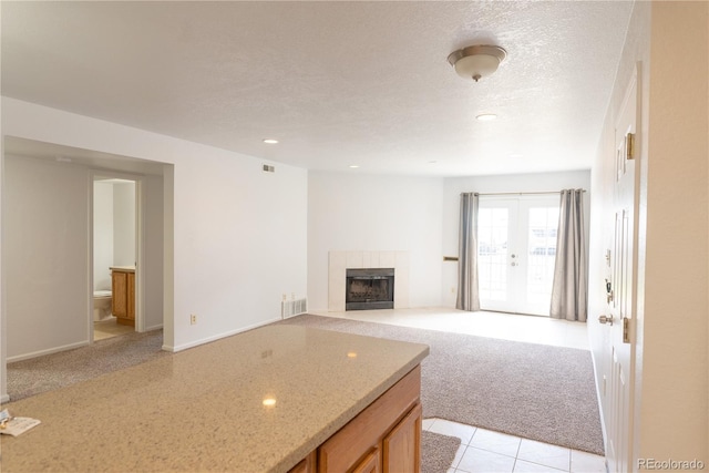 carpeted living room featuring a tile fireplace and a textured ceiling