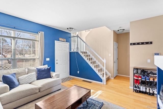 living area featuring stairs, wood finished floors, visible vents, and baseboards