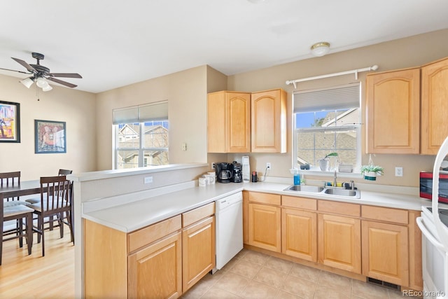 kitchen with dishwasher, a peninsula, a sink, and light countertops