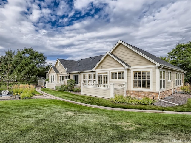back of property featuring a yard and stone siding